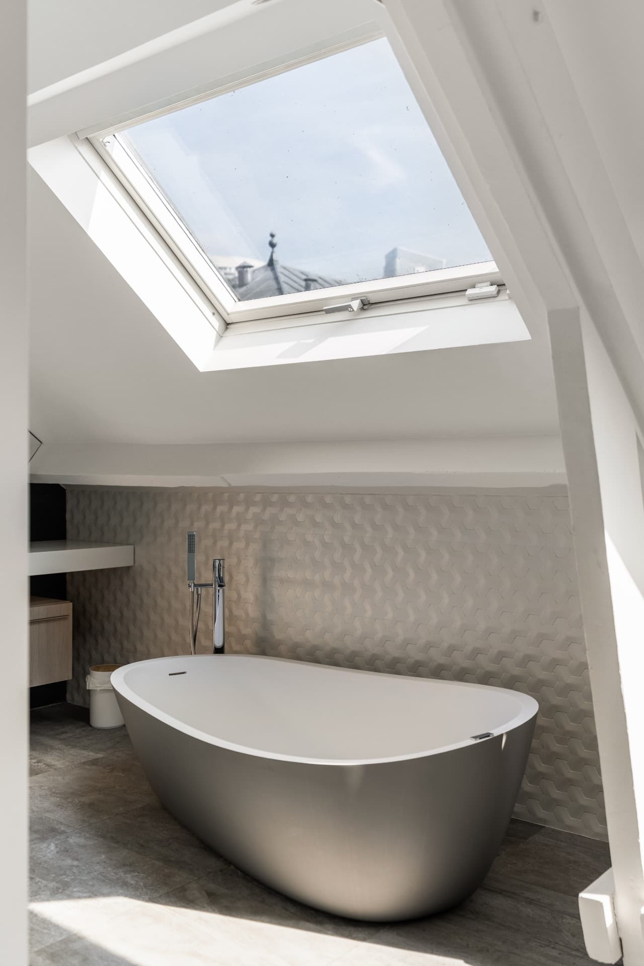 Freestanding bathtub beneath a skylight